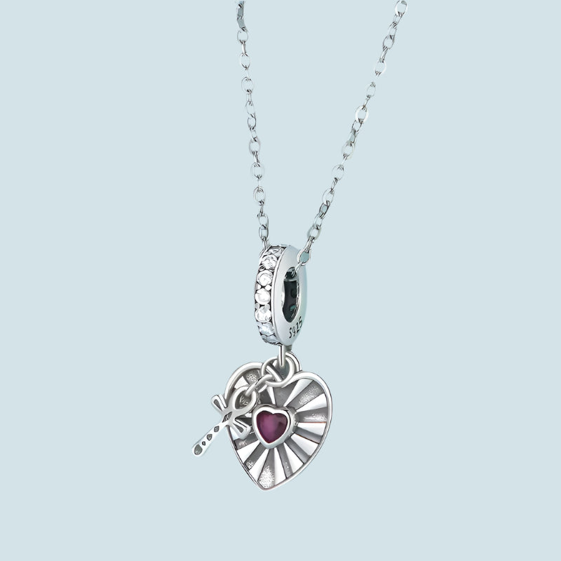 Heart and cross dangle charm in silver with ruby centerpiece and cubic zirconia accents, perfect for charm bracelets.