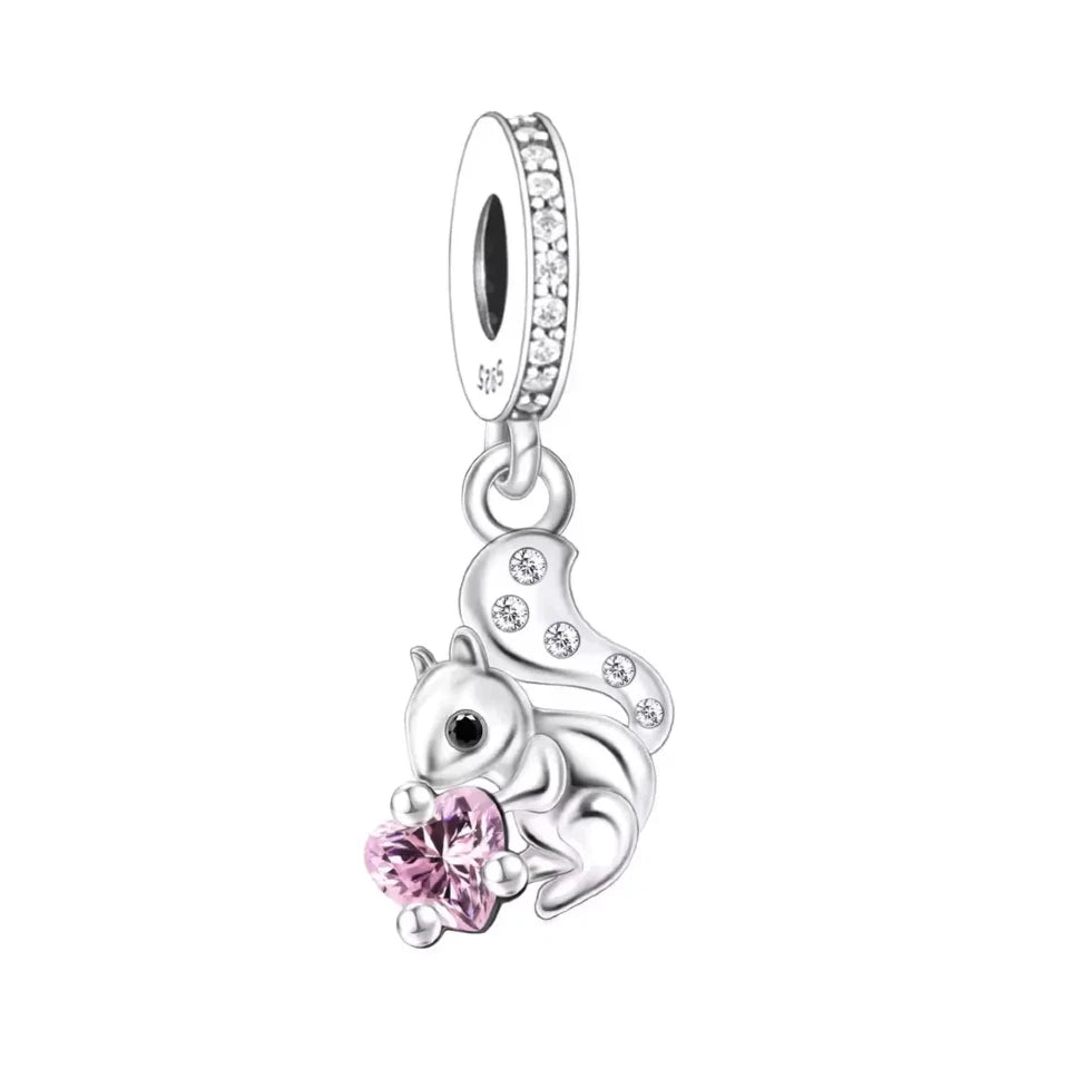Bring a touch of woodland charm to your jewelry collection with this adorable Squirrel Dangle Charm! Crafted from&amp;nbsp;sterling silver, this playful squirrel holds a sparkling pink heart-shaped Cubic Zirconia, symbolizing love and joy. Its bushy tail is accented with dazzling CZ stones, adding a hint of sparkle to this nature-inspired piece. Perfect for animal lovers, nature enthusiasts, or anyone who enjoys cute and whimsical jewelry.