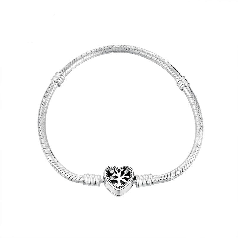 A silver bracelet with a heart-shaped clasp featuring a tree design, on a white background.