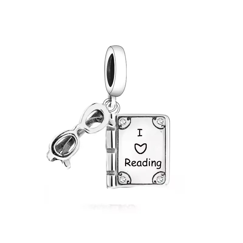 Calling all book lovers! This enchanting dangle charm is the perfect way to showcase your love for reading. Featuring a beautifully detailed book with the words &quot;I ♥ Reading&quot; engraved on the cover, paired with a chic pair of reading glasses, this charm is a must-have for any literary enthusiast.