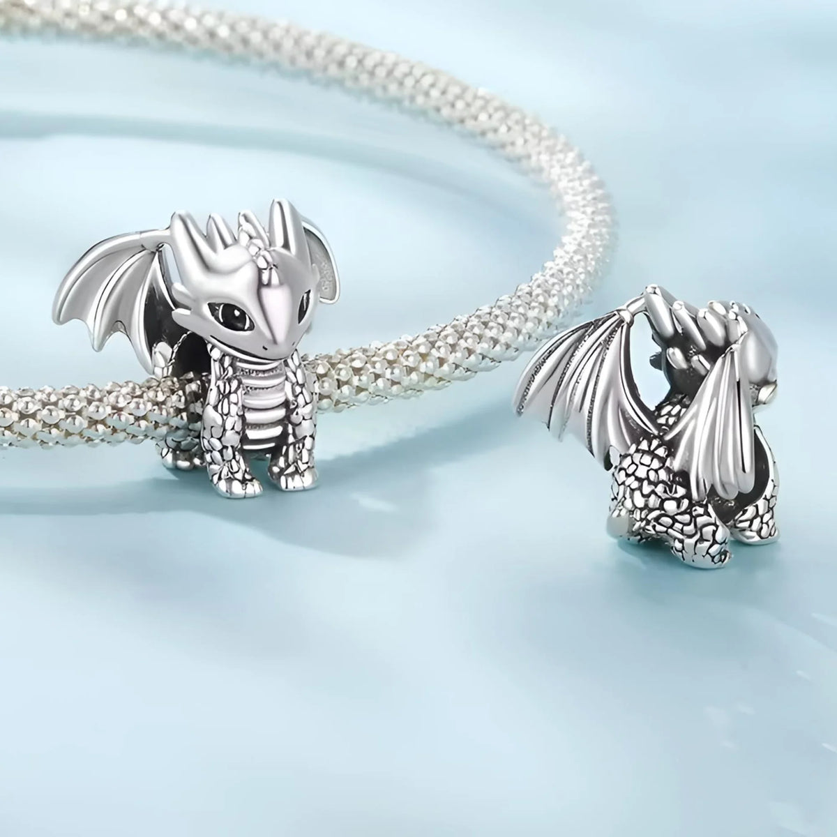 Silver dragon-shaped jewelry pieces on a light blue background