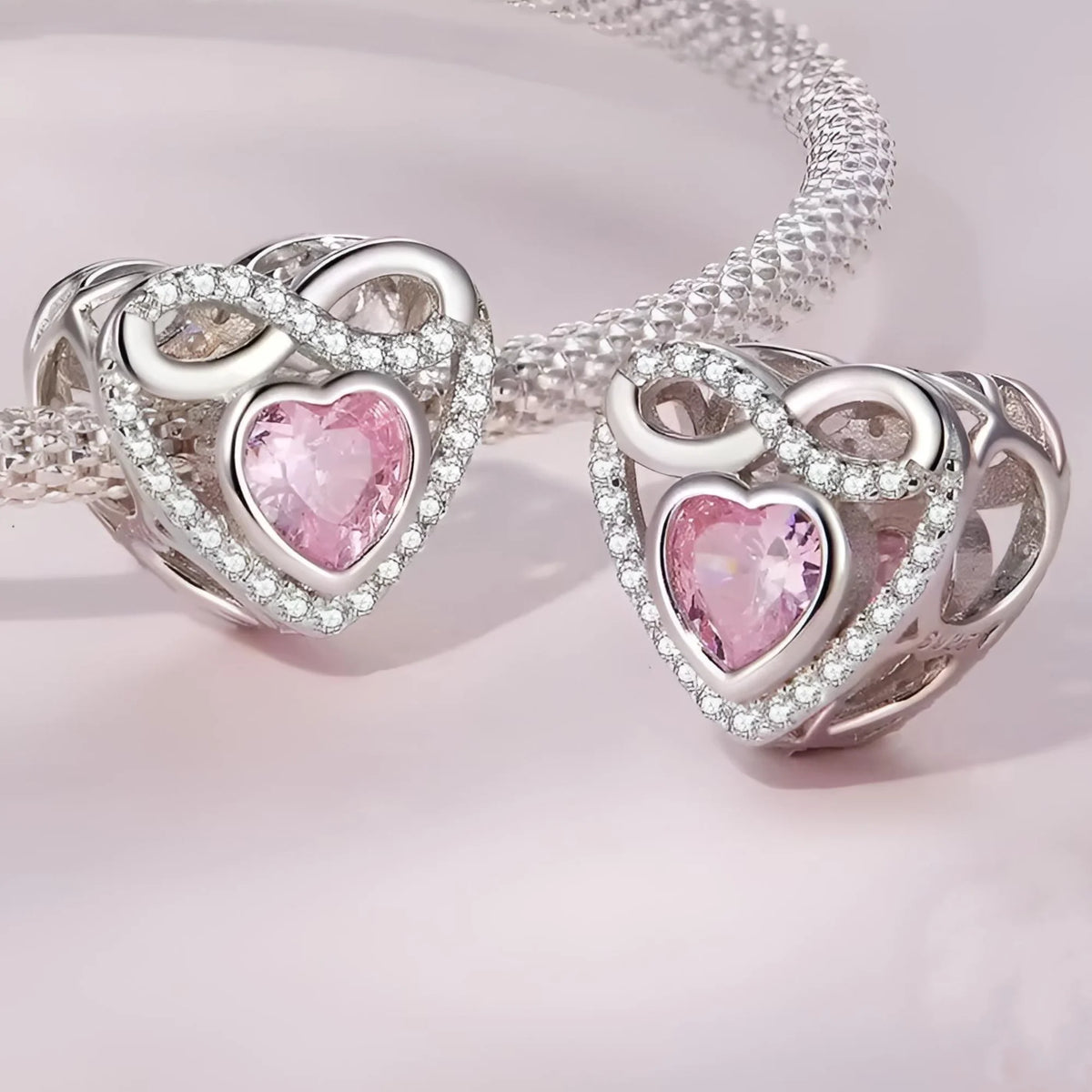 Heart-shaped silver and pink jewelry set on a light pink background