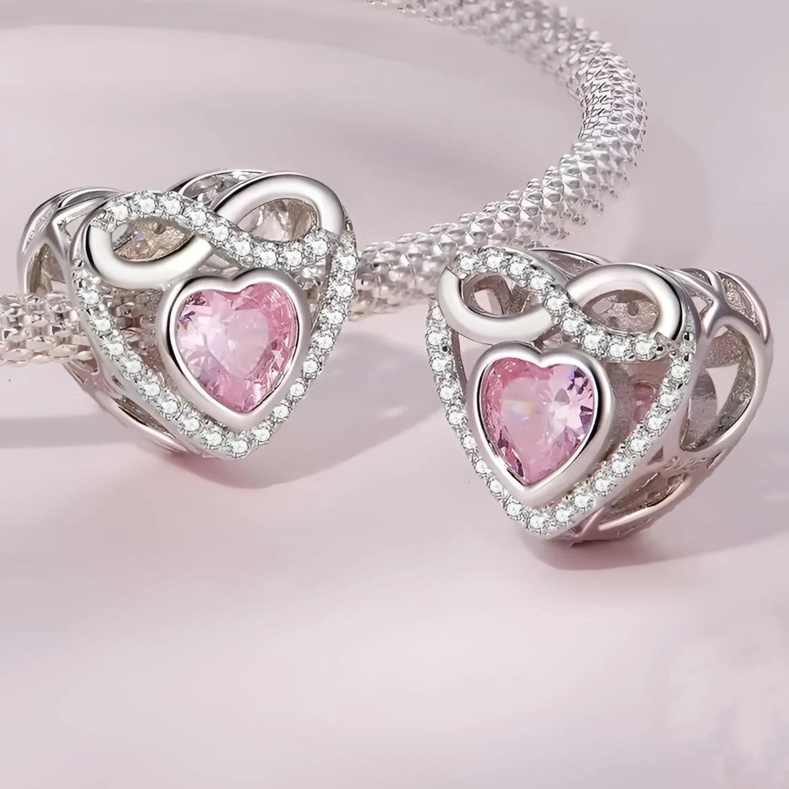 Heart-shaped silver and pink jewelry set on a light pink background