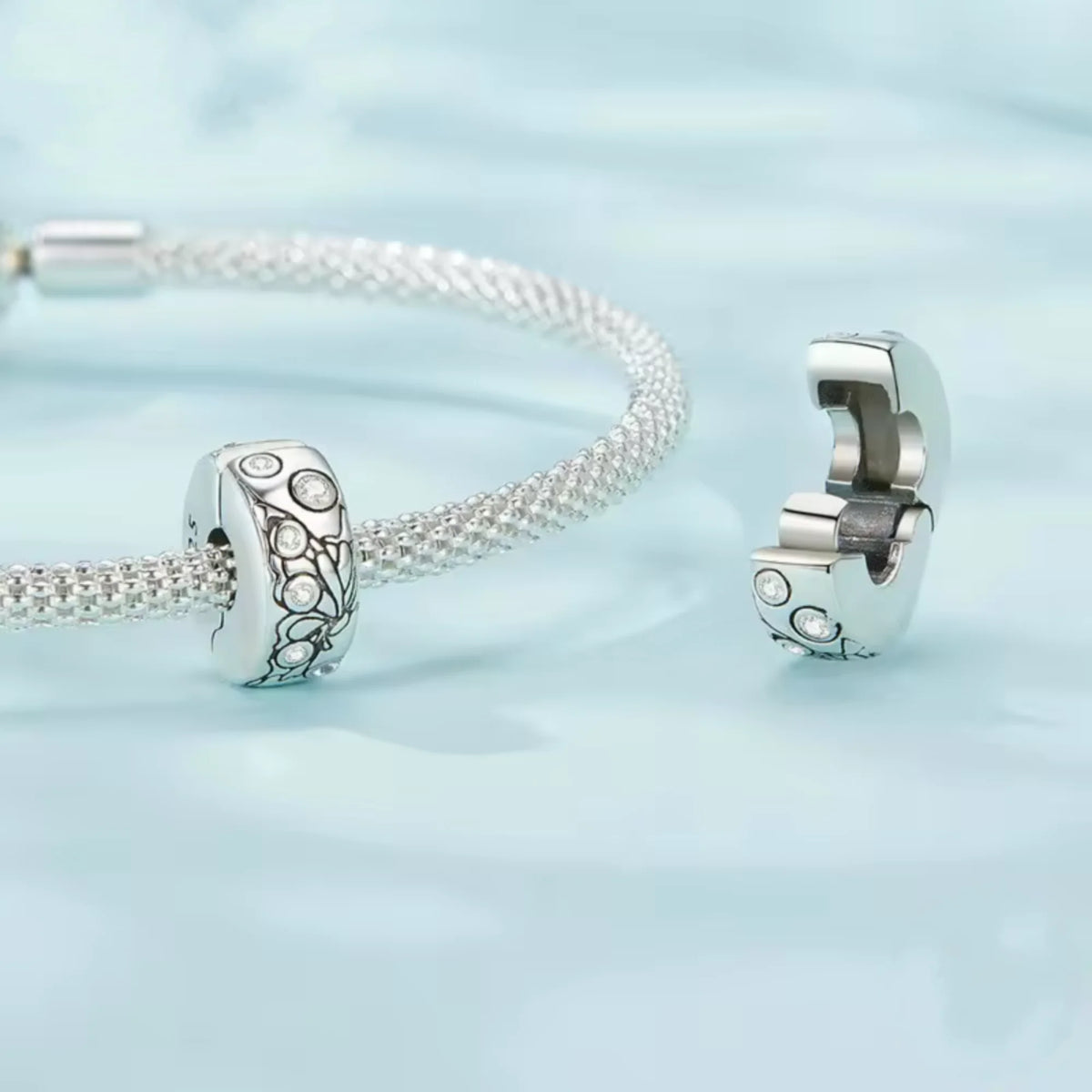 Silver clip charm with butterfly design and embedded cubic zircons on a blue background