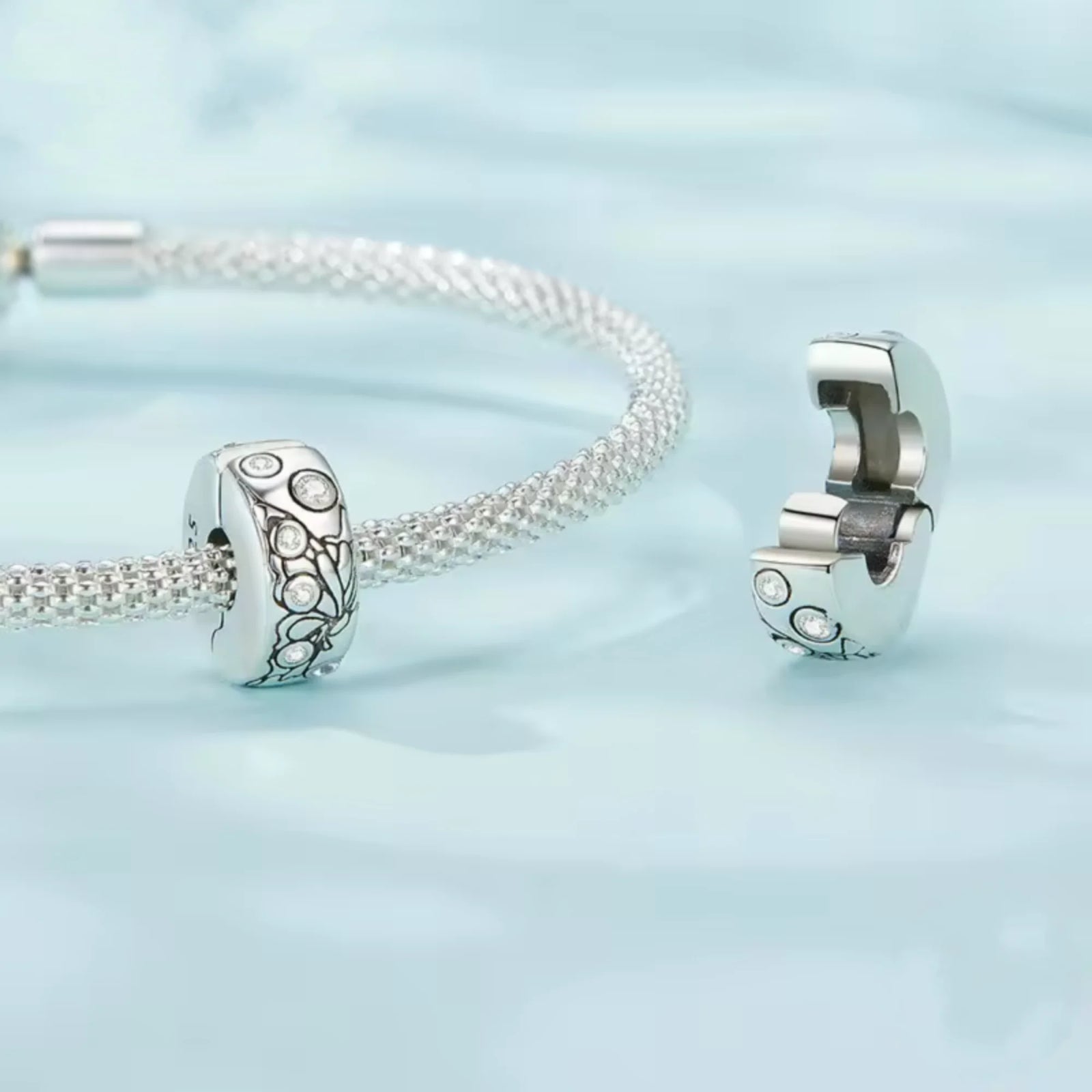 Silver clip charm with butterfly design and embedded cubic zircons on a blue background