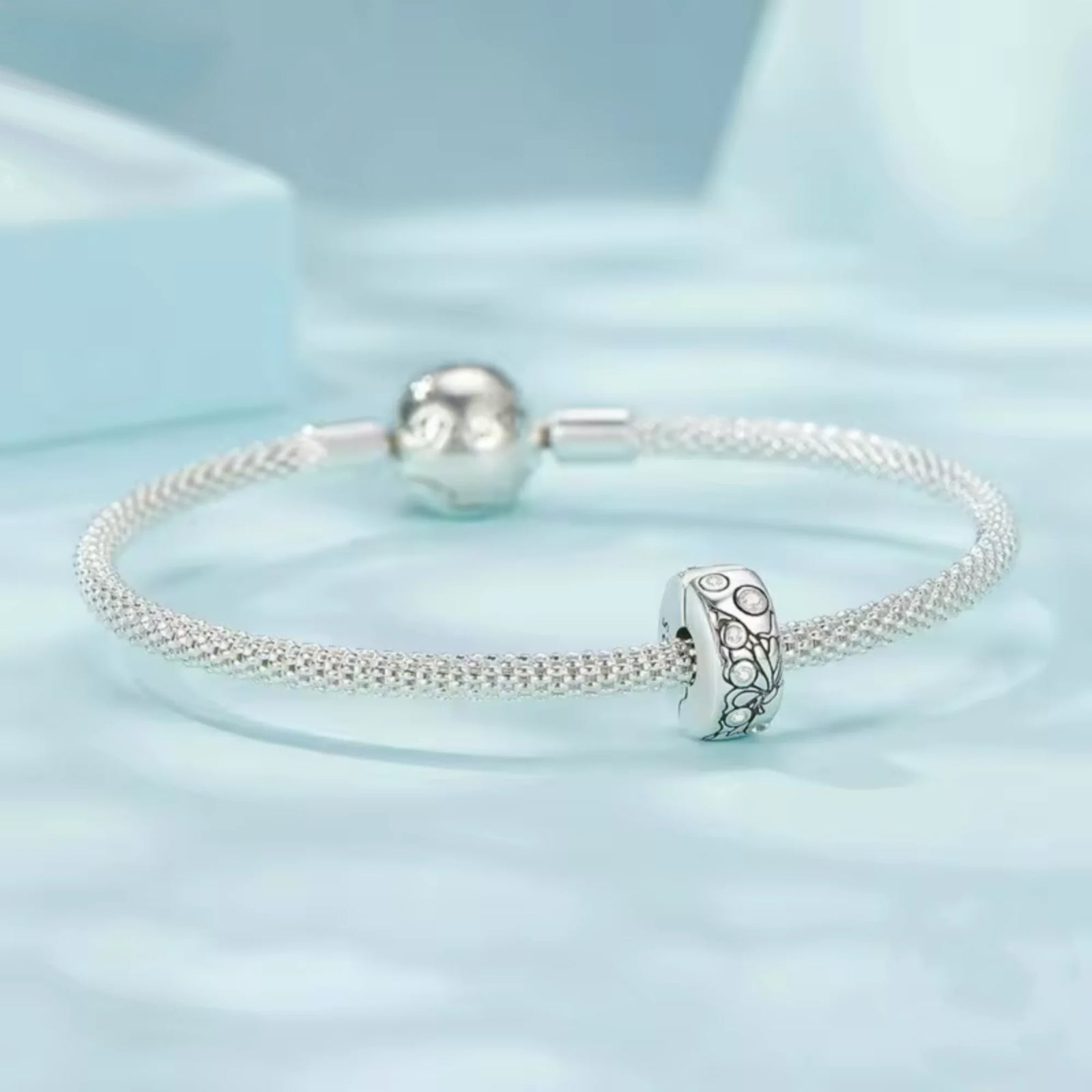 Silver clip charm with butterfly design and embedded cubic zircons on a blue background