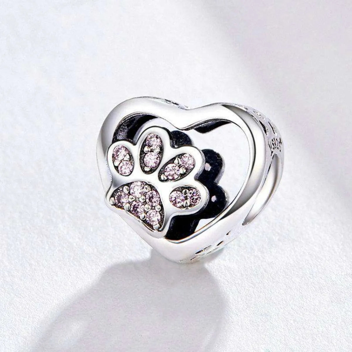 Silver heart-shaped charm with paw print and pink cubic zirconia on a white background
