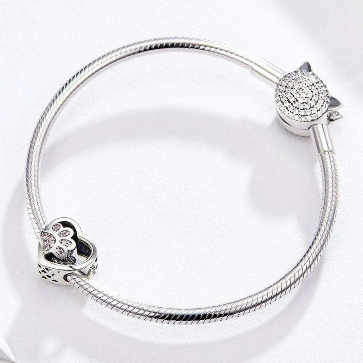 Sterling Silver bracelet with heart-shaped paw print charm with pink cubic zirconia on a white background