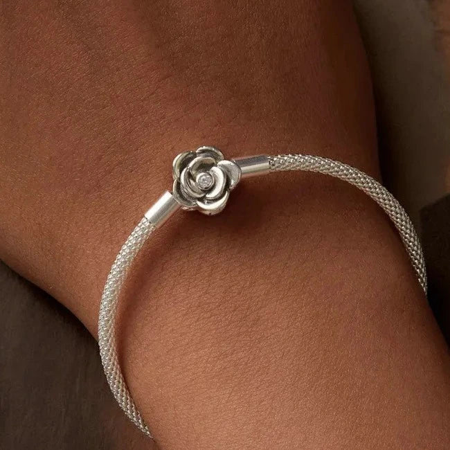 A silver bracelet with a rose-shaped clasp, featuring a cubic zirconia.