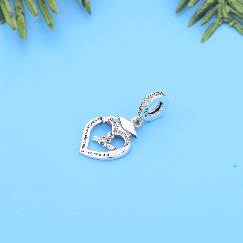 &quot;She Believed She Could, So She Did&quot; sterling silver heart dangle charm with cubic zirconia accent on blue background.