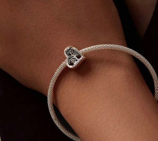 Silver bracelet with heart-shaped "Home Is Where The Heart Is" charm on wrist