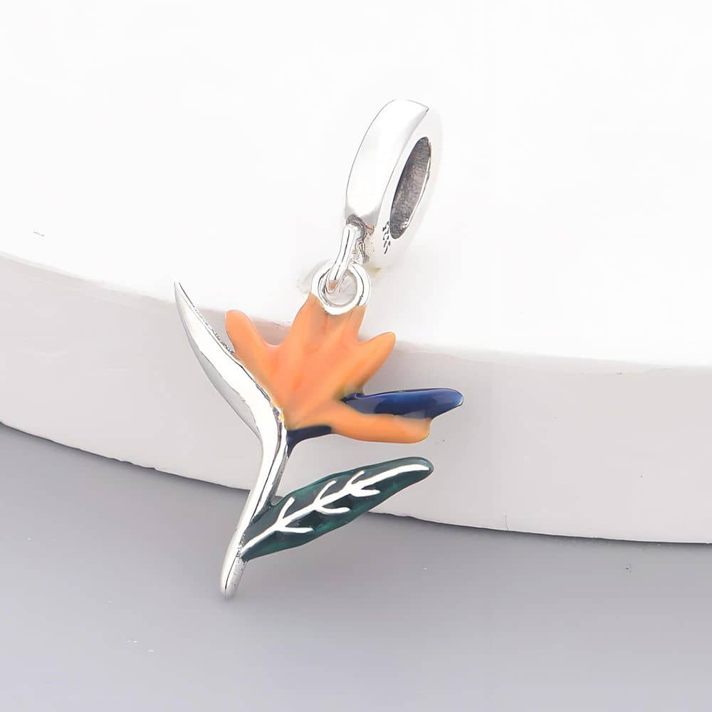 Brighten up your jewelry collection with the stunning Strelitzia Dangle Charm! Inspired by the Bird of Paradise flower, this charm bursts with vibrant orange, blue, and green enamel accents, bringing the beauty of tropical gardens right to your wrist.