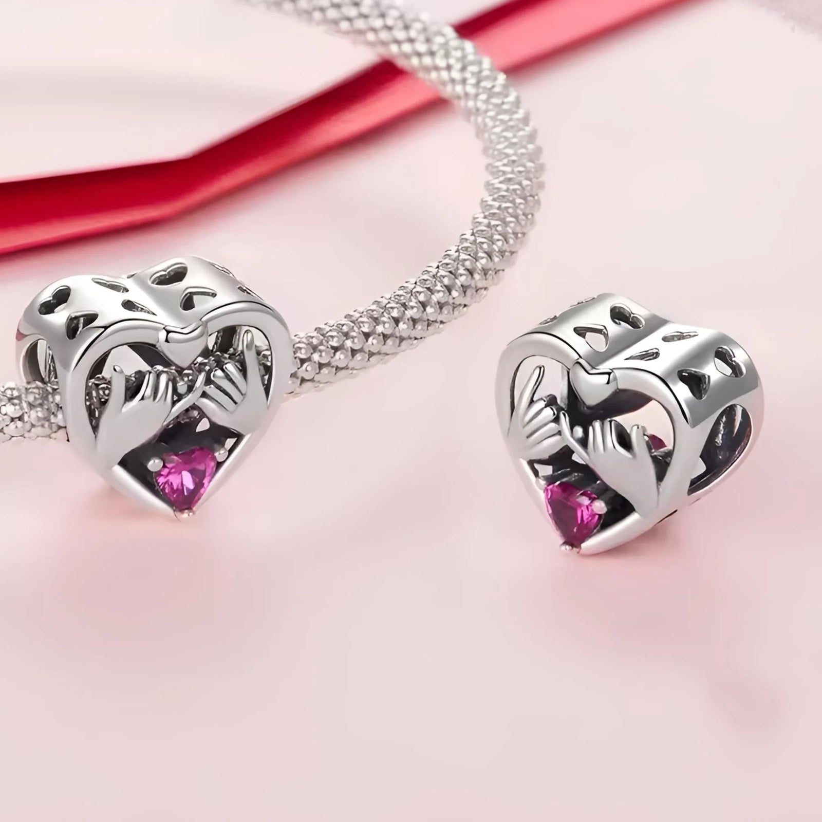 Heart-shaped silver earrings with pink gemstones on a pink background