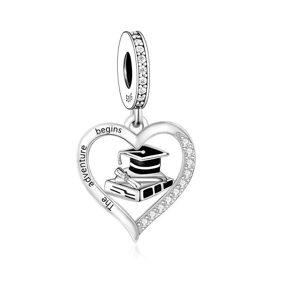 Celebrate new beginnings with this stunning Graduation Dangle Charm! Designed in&nbsp;sterling silver, this elegant charm features an open-heart frame engraved with "The Adventure Begins", surrounding a detailed graduation cap, diploma, and books. The charm is beautifully accented with sparkling Cubic Zirconia stones and black enamel for added contrast and sophistication. Perfect for graduates stepping into their next chapter.