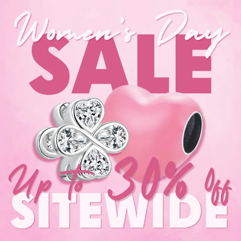 A pink promotional banner for a Women's Day sale, featuring the text 'Women's Day SALE' and 'Up to 30% Off SITEWIDE' alongside a pink heart charm and a silver-toned four-leaf clover charm.