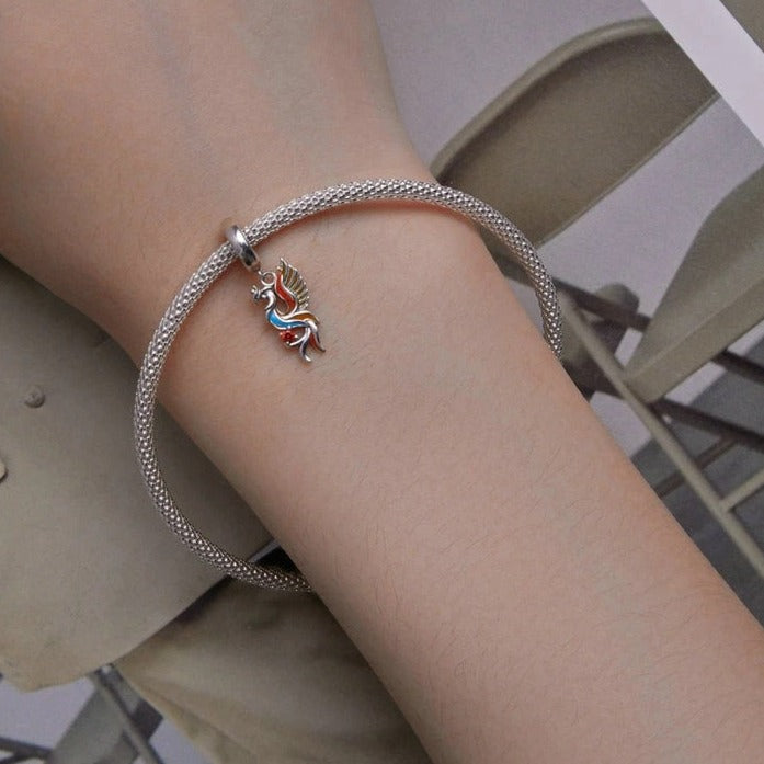 Multicolor Phoenix dangle charm on silver charm bracelet worn on wrist