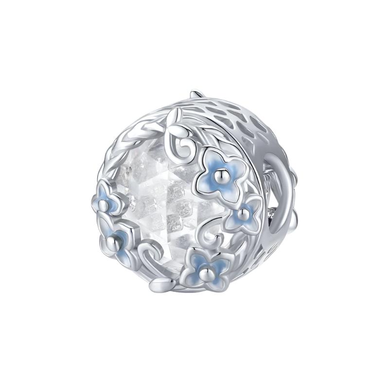 A round sterling silver vintage flower and crystal charm with a white flower and blue cubic zirconia accents.