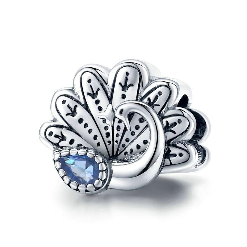 A sterling silver charm featuring a peacock with intricate feathers, with a blue cubic zirconia stone in the center.