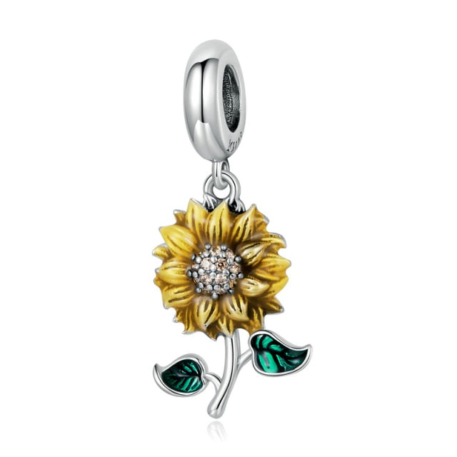 A sterling silver dangle charm with a sunflower design, featuring yellow petals and green leaves, with a clear crystal center.